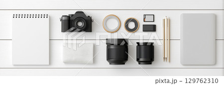 Flat lay of photography equipment and stationery arranged on white wooden surface 129762310