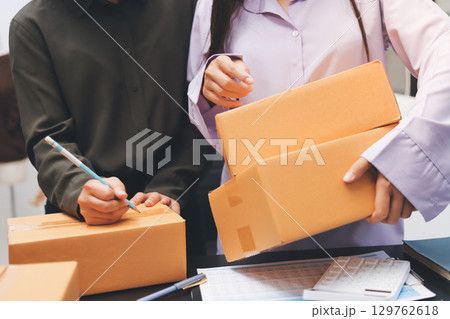 Portrait of Starting small businesses SME owners, two Asian woman check online orders Selling products working with boxs freelance work at home office, sme business online small medium enterprise Portrait of Starting small businesses SME owners, two Asian woman check online orders Selling products working with boxs freelance work at home office, sme business online small medium enterprise 129762618