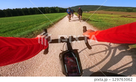 POV road cycling in Vercors overtaking mountain bikers on gravel path, France 129763062