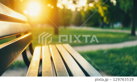 Empty Park Bench Bathed in Golden Sunlight During Sunset. 129763519