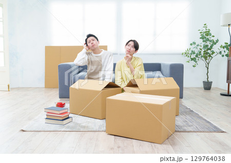 困った表情でダンボールを整理するカップル 129764038