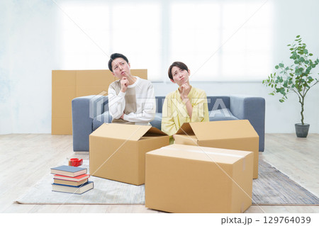 困った表情でダンボールを整理するカップル 129764039