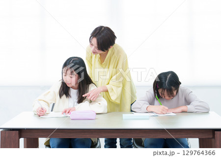 勉強をする女の子 勉強を教えるお母さん 勉強をする女の子 勉強を教えるお母さん 129764366