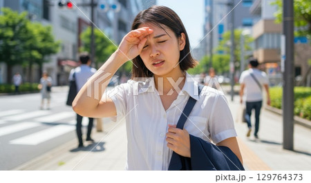 酷暑で熱そうに汗を拭う女性 129764373