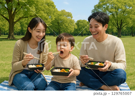 公園でお弁当を食べる親子 129765007