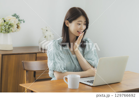 部屋でパソコンを見る女性 部屋でパソコンを見る女性 129766692
