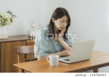 部屋でパソコンを見る女性 129766693