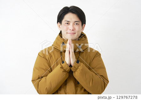 ダウンジャケットを着た男性　合掌して祈る　白背景　カメラ目線 129767278