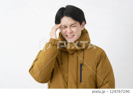 ダウンジャケットを着た男性　頭痛　白背景 129767290