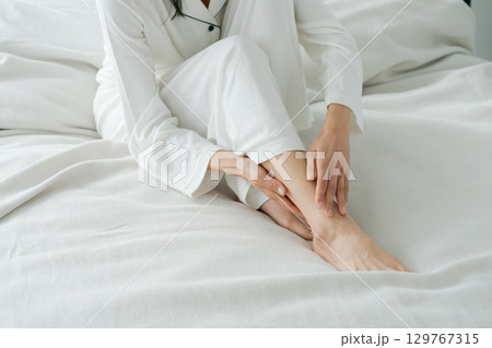 ベッドに座り足をマッサージする女性 129767315