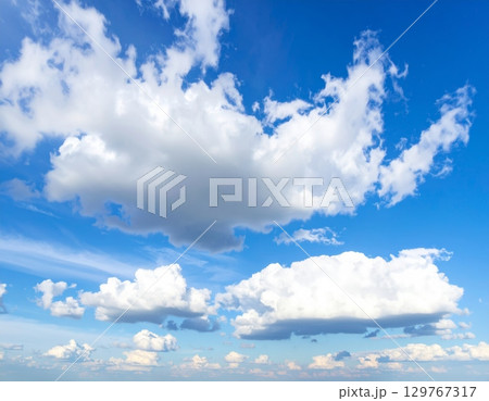 Beautiful and fluffy white clouds float in the vast blue summer sky Beautiful and fluffy white clouds float in the vast blue summer sky 129767317