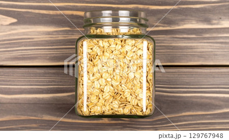 Dry raw organic oatmeal and buckwheat cereal grains in glass jars on a white background Dry raw organic oatmeal and buckwheat cereal grains in glass jars on a white background 129767948