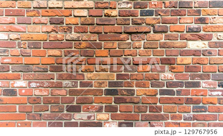 An old red brick wall with a textured pattern of cement and stone blocks 129767956