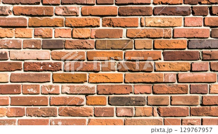 An old red brick wall with a textured pattern of cement and stone blocks 129767957