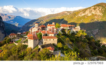 Landscape view of a picturesque European mountain village with a church and houses, overlooking the sea 129767969