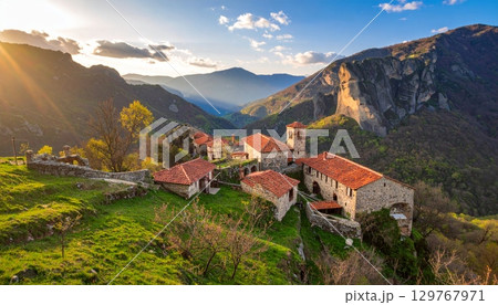 Landscape view of a picturesque European mountain village with a church and houses, overlooking the sea 129767971