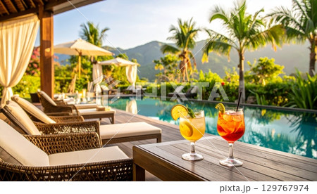 Sipping a refreshing tropical cocktail while relaxing in a chair by the beach, surrounded by a paradise of palm trees and the clear blue ocean Sipping a refreshing tropical cocktail while relaxing in a chair by the beach, surrounded by a paradise of palm trees and the clear blue ocean 129767974