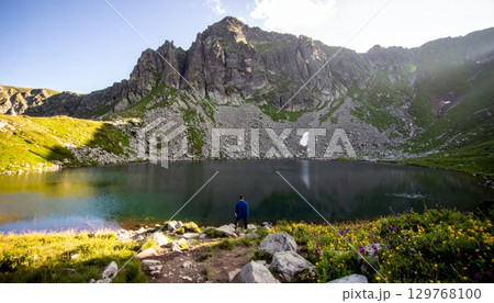 Autumn landscape with a tranquil mountain lake reflecting the surrounding peaks, a forest, and a clear sky Autumn landscape with a tranquil mountain lake reflecting the surrounding peaks, a forest, and a clear sky 129768100