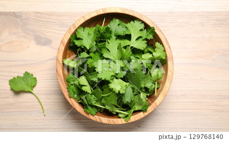 Fresh organic green salad with parsley, spinach, and other vegetables in a wooden bowl on a white isolated background 129768140
