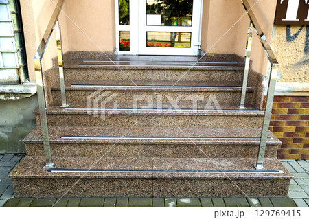 Detail of a house facade. New granite stairs with metal railings. 129769415