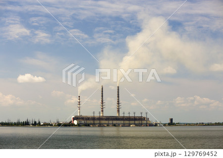 Thermal power station tall pipes with thick smoke reflected in lke water surface. Pollution of environment concept. Thermal power station tall pipes with thick smoke reflected in lke water surface. Pollution of environment concept. 129769452