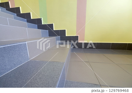 Wide staicase covered with ceramic tiles indoors in a house interior. 129769468