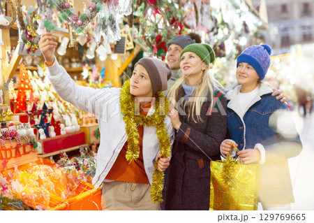 Family choosing Christmas decoration at Christmas market in evening Family choosing Christmas decoration at Christmas market in evening 129769665