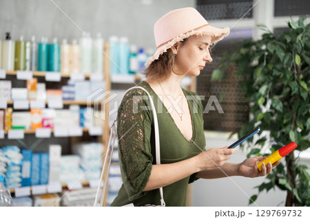 Woman in pharmacy scans QR code on mosquito repellent 129769732