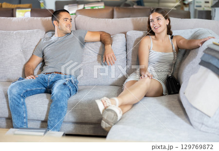 In store,husband and wife are sitting on gray sofa and choose upholstered furniture for living room In store,husband and wife are sitting on gray sofa and choose upholstered furniture for living room 129769872
