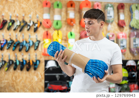 Young man view rope cable for climbing and evaluate its thickness Young man view rope cable for climbing and evaluate its thickness 129769943