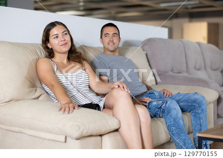 In store,husband and wife are sitting on gray sofa and choose upholstered furniture for living room In store,husband and wife are sitting on gray sofa and choose upholstered furniture for living room 129770155