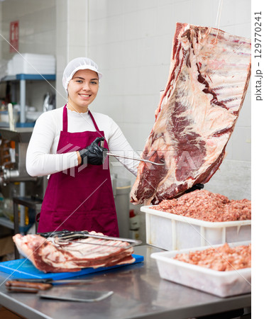 Young woman butcher holding beef ribs Young woman butcher holding beef ribs 129770241