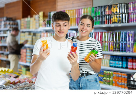 Young married couple chooses drink bottle in store to buy them Young married couple chooses drink bottle in store to buy them 129770294