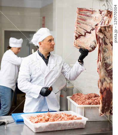 Confident male butcher holding big chunk of beef ribs is prepared in butchery Confident male butcher holding big chunk of beef ribs is prepared in butchery 129770304