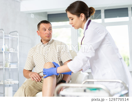 Middle-aged man patient having his knee examined by doctor Middle-aged man patient having his knee examined by doctor 129770514