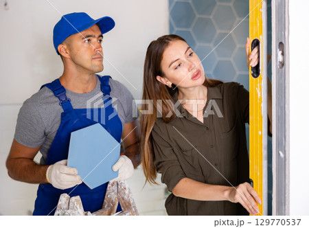 Owner of apartment checks verticality of wall, made by professional builder, using building level Owner of apartment checks verticality of wall, made by professional builder, using building level 129770537