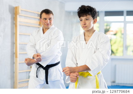 Individual karate lesson for teenager - fighting position of teenager and coach during karate training in gym 129770684