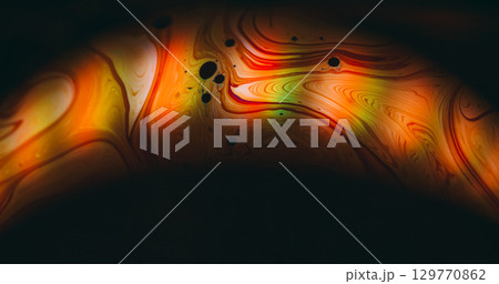 Glow arch blur. Rainbow soap flow. Orange red green ink round light lens on black background. Color blending liquid abstract texture. 129770862