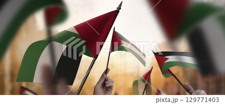 Palestine flags in their hands on a blurred urban background 129771403