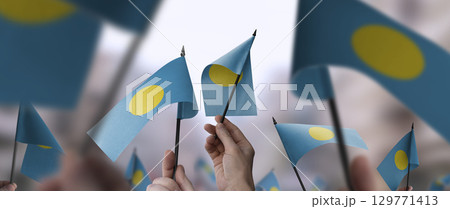 Palau flags in their hands on a blurred urban background 129771413