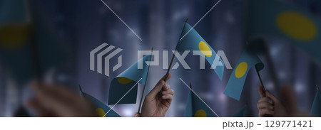 Palau flags in their hands on a blurred urban background 129771421