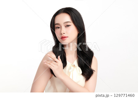 A beautiful young Asian woman with clean, fresh skin against a white background. Skincare, facial treatment, cosmetology, beauty, and spa. An elegant portrait of an Asian woman. 129771460