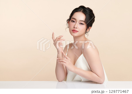 A beautiful young Asian woman with clean, fresh skin against a beige background. Skincare, facial treatment, cosmetology, beauty, and spa. An elegant portrait of an Asian woman. A beautiful young Asian woman with clean, fresh skin against a beige background. Skincare, facial treatment, cosmetology, beauty, and spa. An elegant portrait of an Asian woman. 129771467
