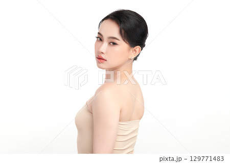A beautiful young Asian woman with clean, fresh skin against a white background. Skincare, facial treatment, cosmetology, beauty, and spa. An elegant portrait of an Asian woman. 129771483