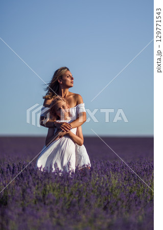 Mother Daughter Lavender. Woman embraces girl in lavender field on sunny day for family portrait. 129771543