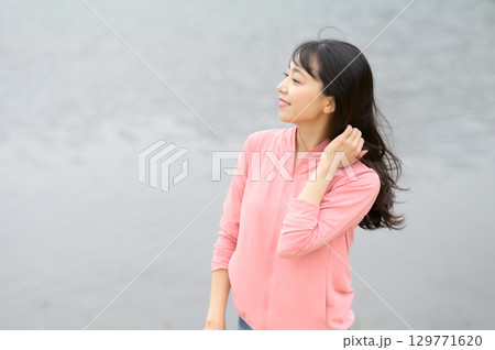 公園の水際で佇む女性 129771620