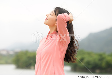 公園の水際で佇む女性 129771626