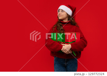 Girl in Santa hat holds Christmas gifts 129772324