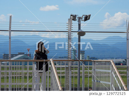 夏の昼の小松空港の展望台で風景を見る女性観光客の姿 129772525