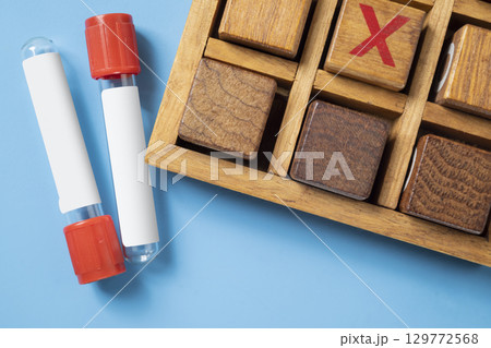 Closeup view of an empty test tube with a wooden tic tac toe game on a blue background. Mockup or Copy space. Concept of healthcare and medicine Closeup view of an empty test tube with a wooden tic tac toe game on a blue background. Mockup or Copy space. Concept of healthcare and medicine 129772568